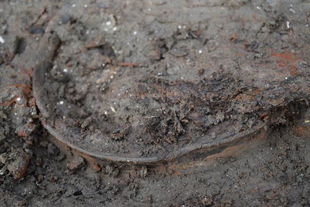 The rim of a vessel just beginning to emerge from the silt.