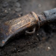 Burnt socketed axe head with charred haft in the background.